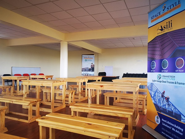 Desks and benches have been kept in order in a class room, which has some flex and banners on their walls.