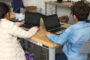 Two little kids are sitting on a table and learning on laptop.